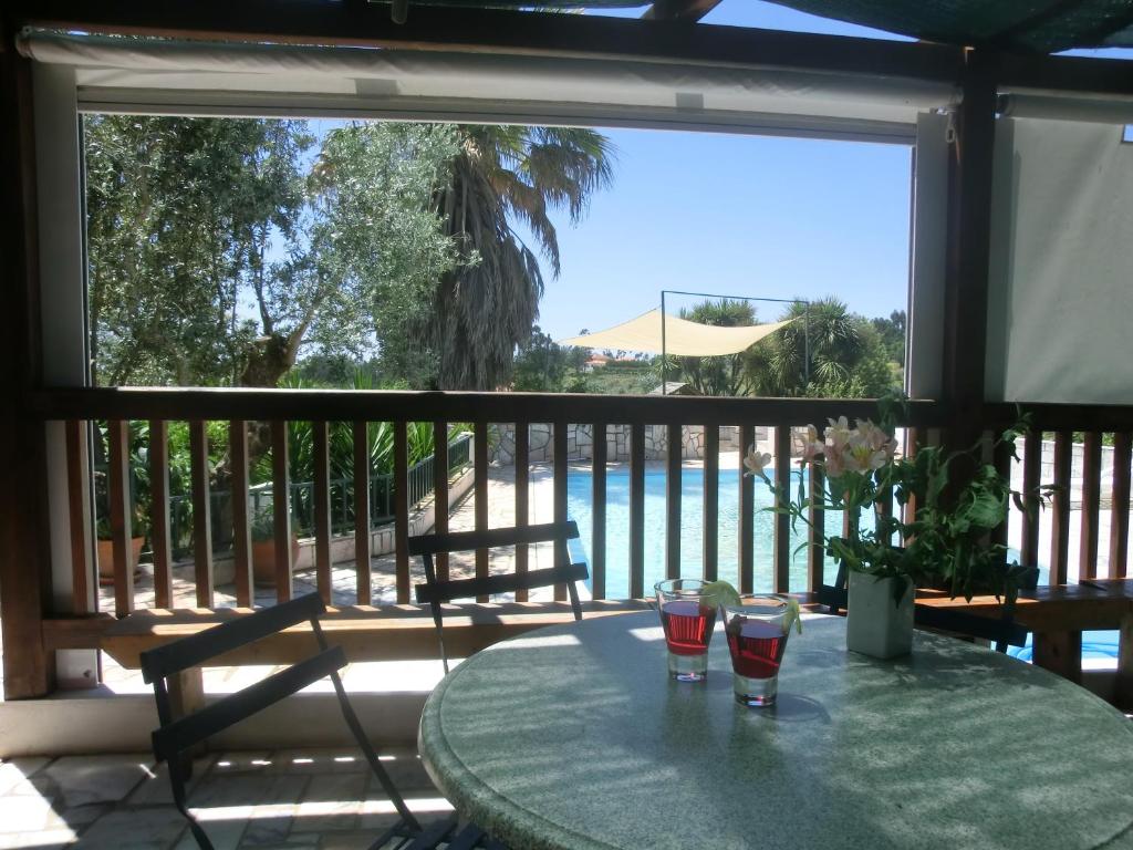 Junceira雷东多小屋酒店的一个带两杯眼镜的桌子和一个带游泳池的阳台