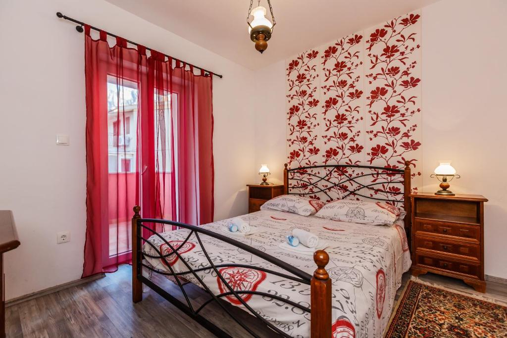 马卡尔斯卡Apartments Antonio的一间卧室配有床和红色窗帘的窗户