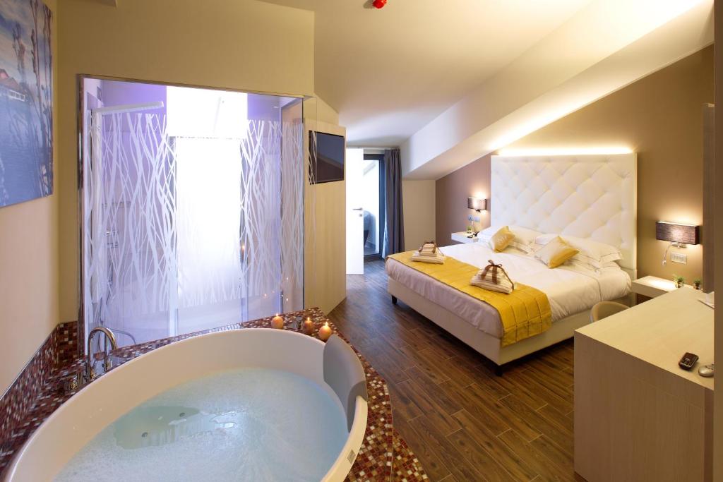 Caramagna PiemonteHotel Terre Dei Salici的卧室设有大浴缸和一张床