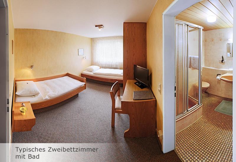斯图加特斯图加特科那申酒店的一间卧室配有一张床和一张带电脑的书桌