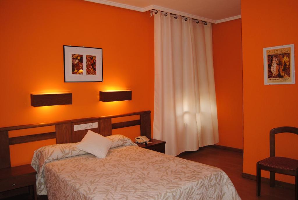昆卡佩德罗托雷斯酒店的一间卧室拥有橙色的墙壁,配有一张床和椅子