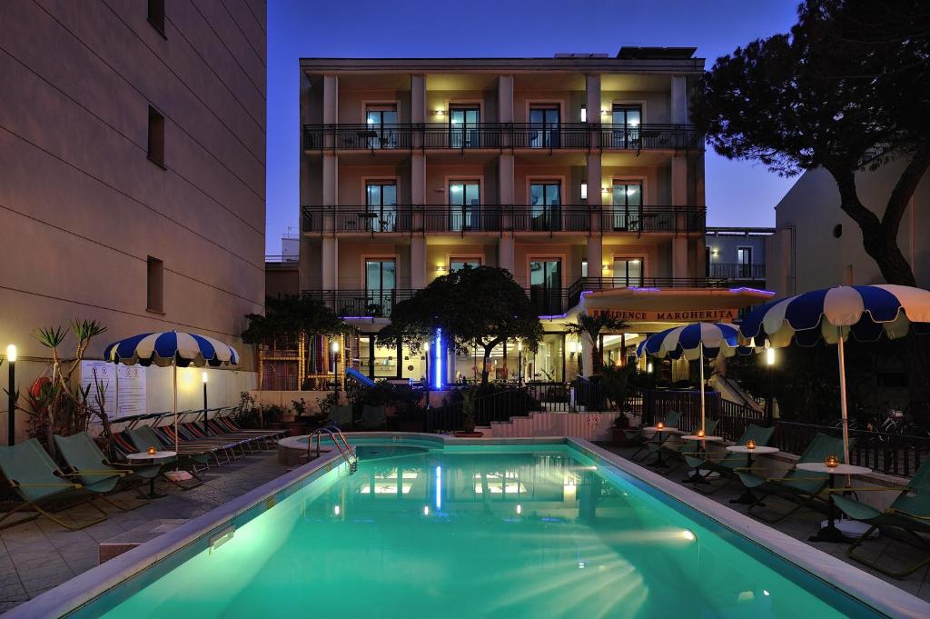 卡托利卡Residence Margherita的夜间在酒店前的游泳池