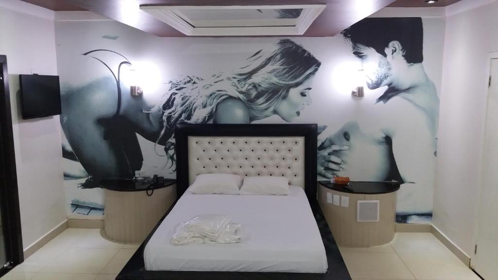 São JorgeShopping Motel Santa Maria do Pará的卧室配有一张床,墙上挂有绘画作品