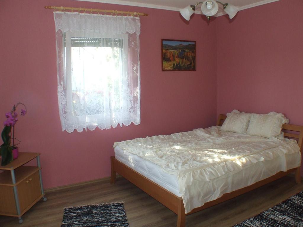 鲍洛通费尼韦什Pajtás Apartman的卧室配有白色的床和粉红色的墙壁