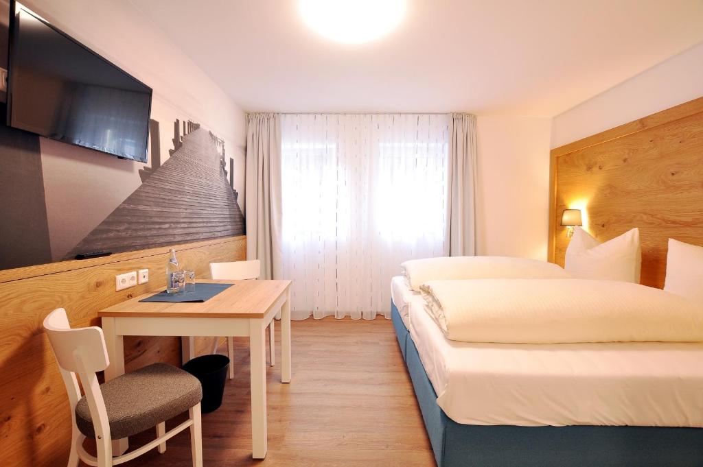 瓦尔滕霍芬Gästehaus zur Krone的酒店客房配有一张床、一张桌子和一张床