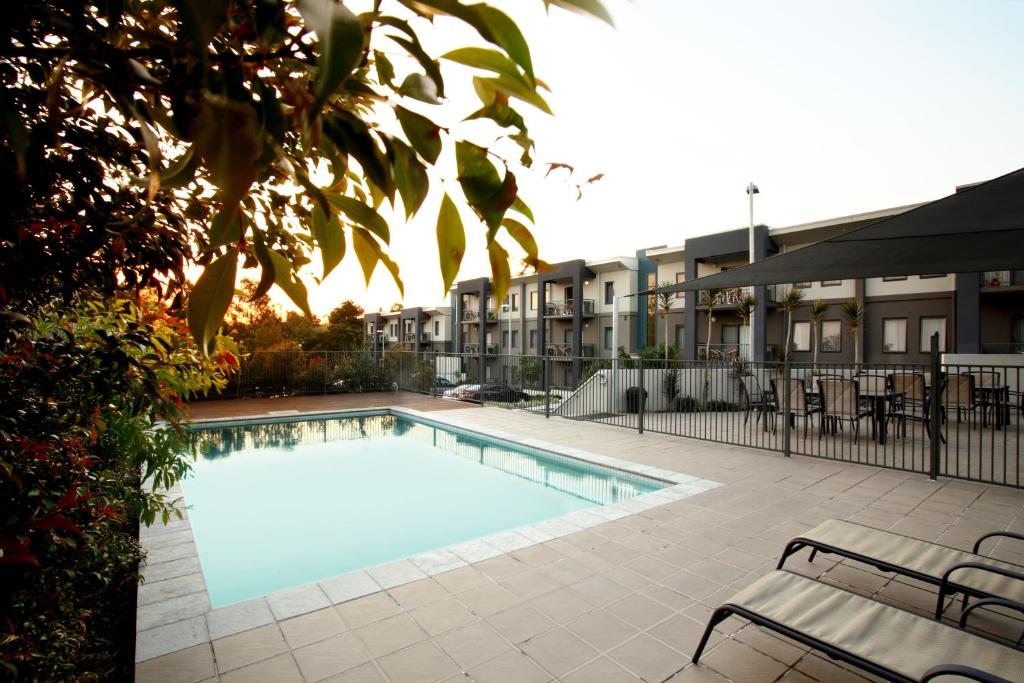 伊普斯维奇奎斯特伊普斯威奇公寓式酒店的一座游泳池,旁边设有长凳