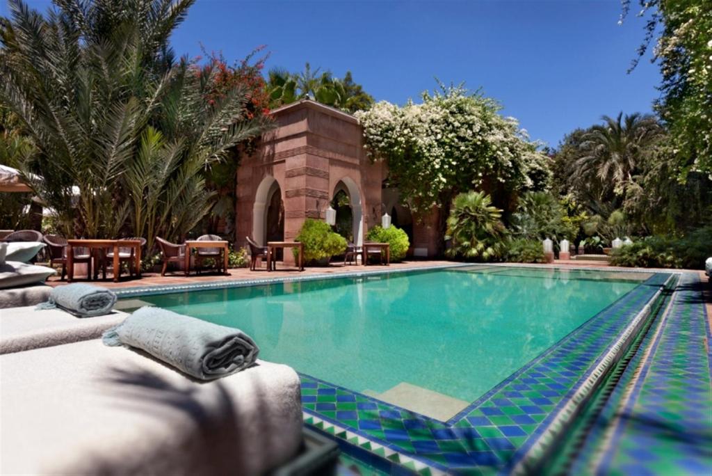 马拉喀什瑞兹兰德博宫酒店及SPA的一个带椅子的游泳池以及一座房子
