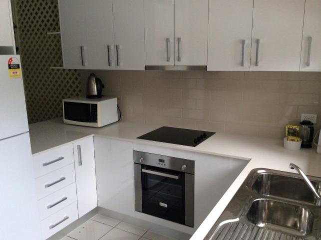 米申海滩奇拉玛4号公寓的厨房配有白色橱柜、水槽和微波炉