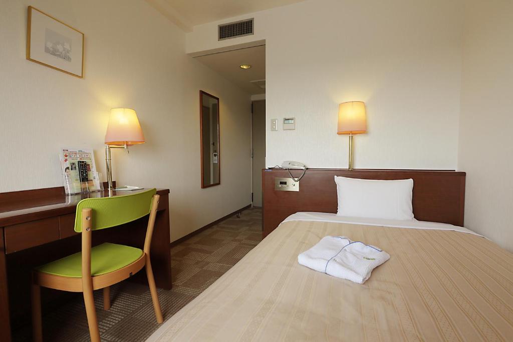 东村山市久米川翼酒店的酒店客房配有一张床、一把椅子和一张书桌
