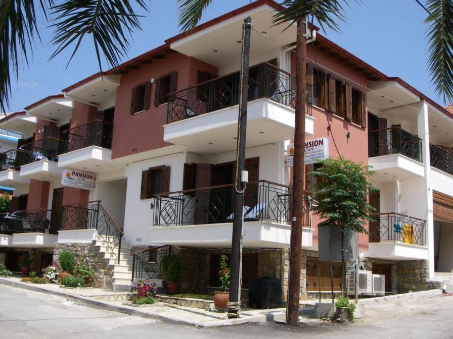 阿莫利亚尼岛Pansion Evi的粉红色和白色的建筑,设有阳台和棕榈树