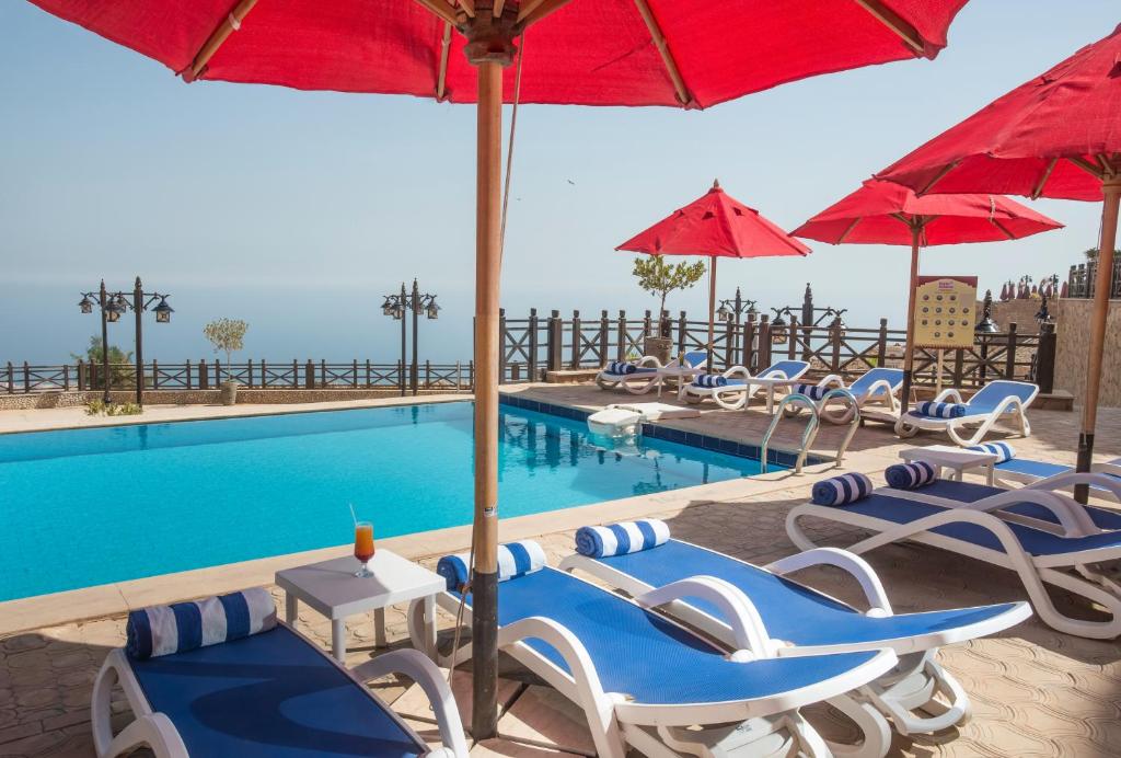 艾因苏赫纳Porto El Jabal Hotel的一个带躺椅和遮阳伞的游泳池