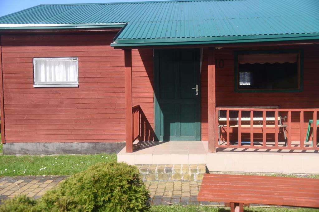 姆热日诺Nestor Domki的一座红色的房子,有绿色的屋顶和长凳