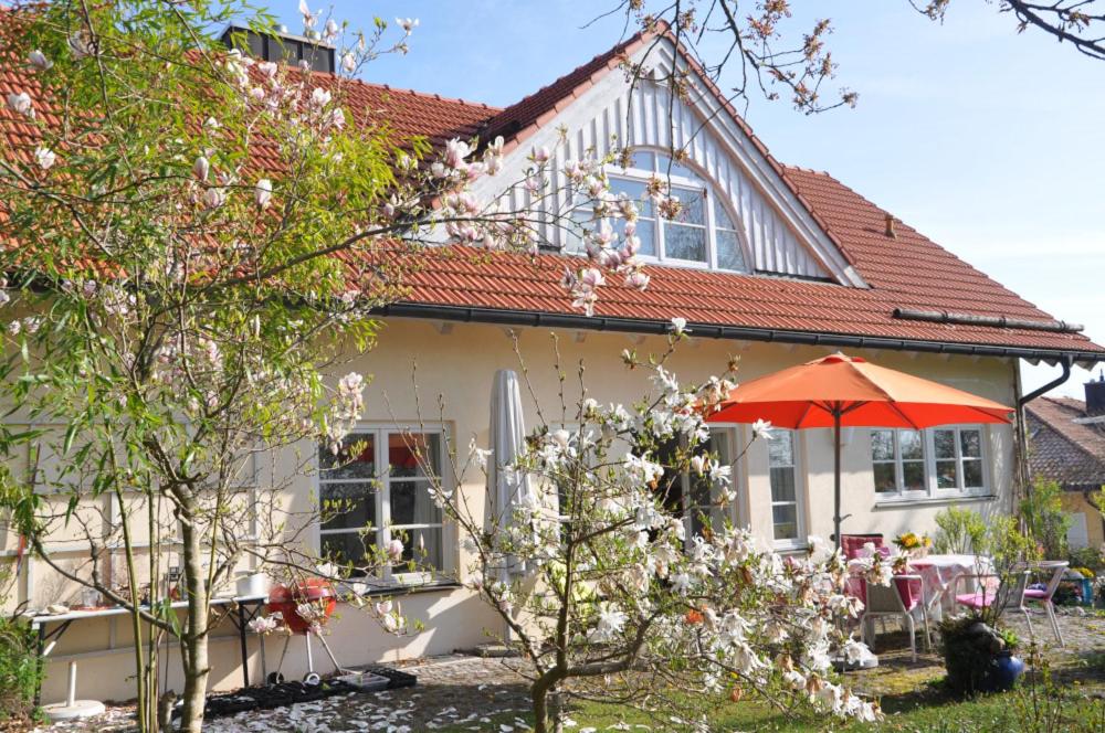 Icking巴伐利亚慕尼黑住宿加早餐酒店的前面有橙色伞的白色房子