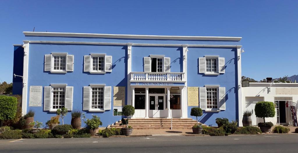 塔尔巴赫Tulbagh Travelers Lodge - Cape Dutch Quarters的蓝色的房子,有白色百叶窗和门廊
