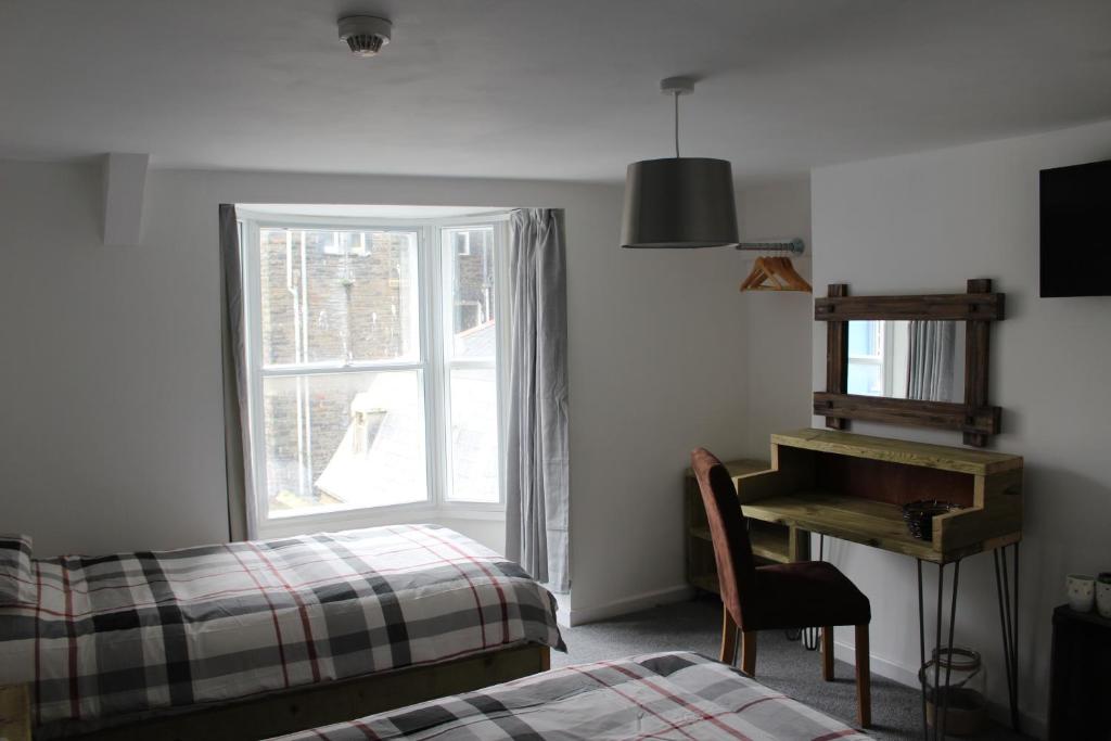 阿伯里斯特威斯The Pier Hotel的卧室配有一张床和窗户旁的钢琴