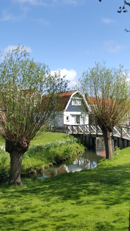 欣德洛彭Vakantiehuis uus Klinte Hindeloopen的一座有两棵树的河上桥梁的房子