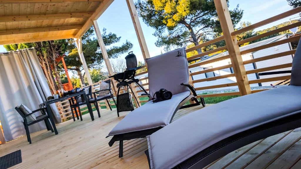 耶泽拉Adrijela Mobile Home的木甲板上设有带椅子和长凳的门廊