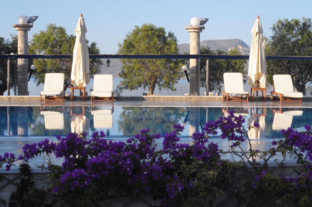 阿达玛斯拉佳达海滩酒店的游泳池配有椅子和遮阳伞,鲜花紫色
