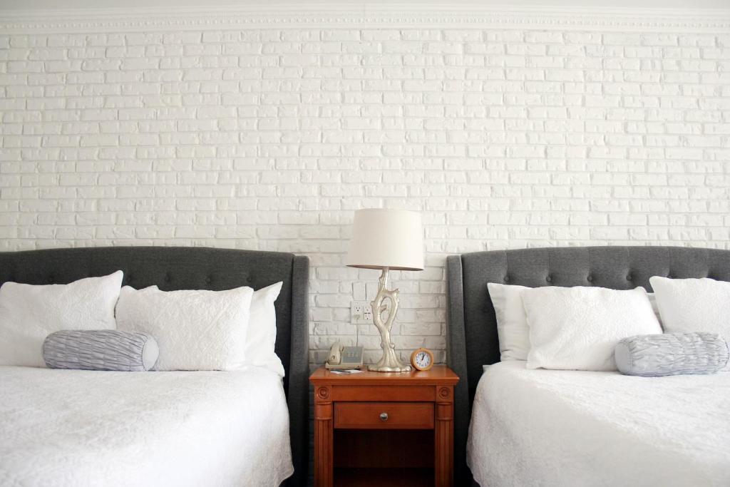 金斯顿绿色英亩旅馆的两张带白色枕头的床和一张带台灯的桌子