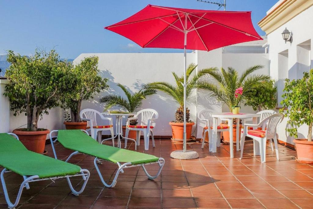 内尔哈百夫长公寓 的一个带桌椅和红色遮阳伞的庭院