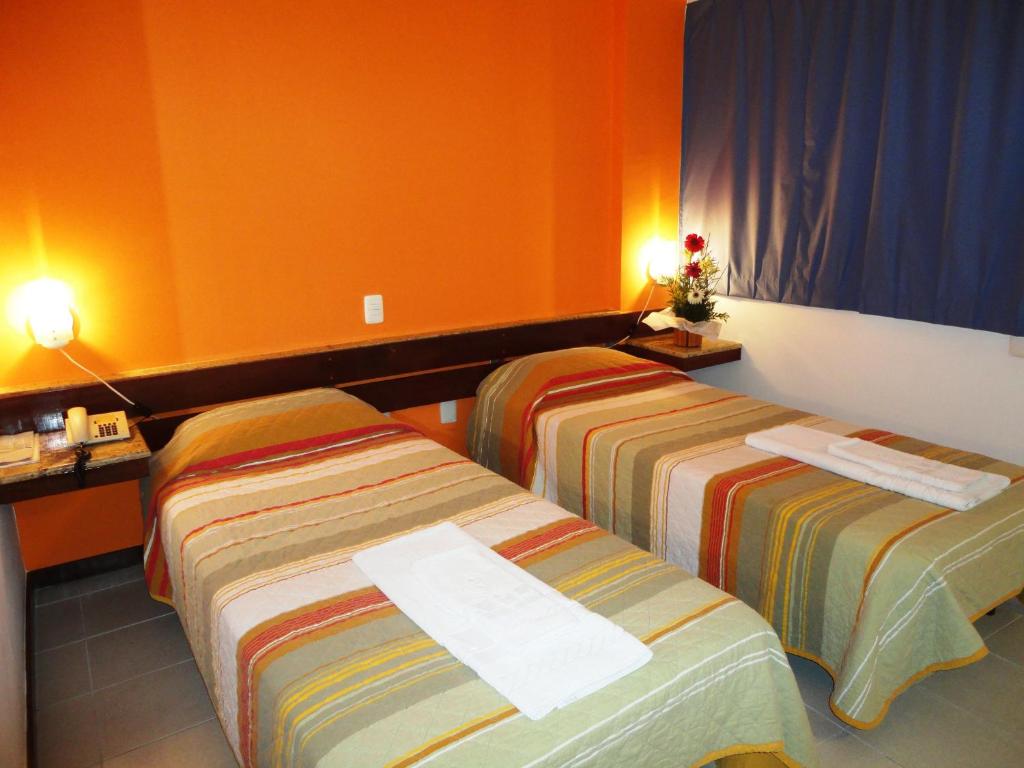 萨尔瓦多比萨广场酒店 的橙色墙壁的酒店客房内的两张床