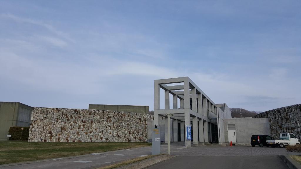 幕别町十胜娜芒温泉酒店的停车场旁一座带大石墙的建筑