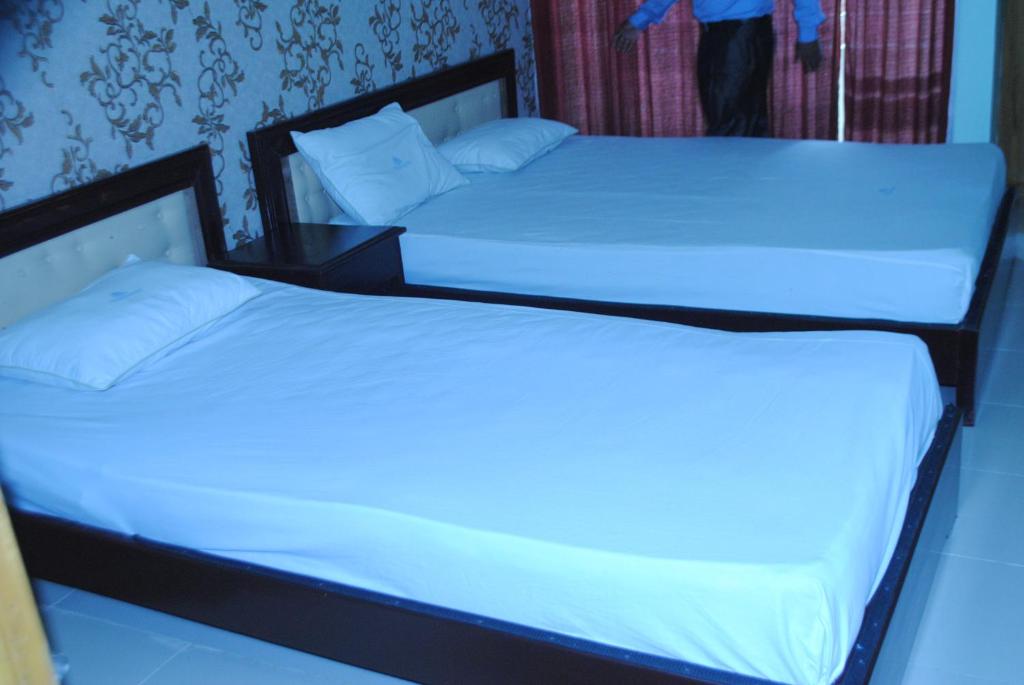 库克斯巴扎Shopno Bilash Holiday Suites的配有2张床的带白色床单和枕头的客房