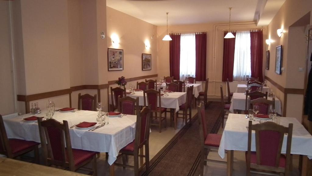 诺维萨德娜莎提维达瓦宾馆的餐厅配有桌椅和白色的桌布