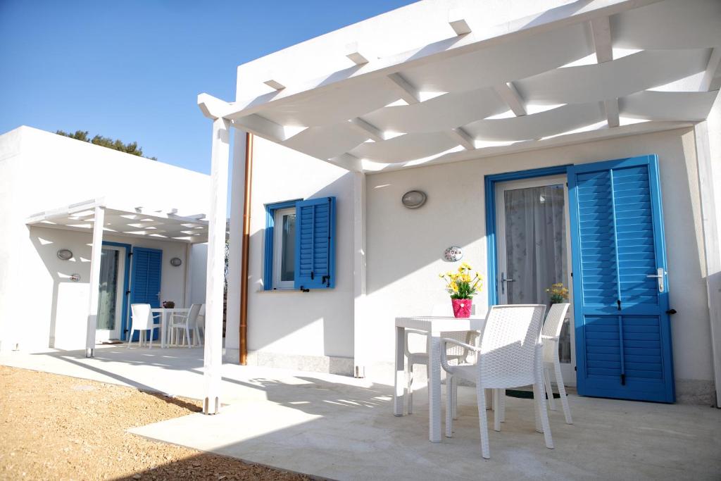 法维尼亚纳Plaia Resort的白色的房子,配有蓝色百叶窗和桌椅