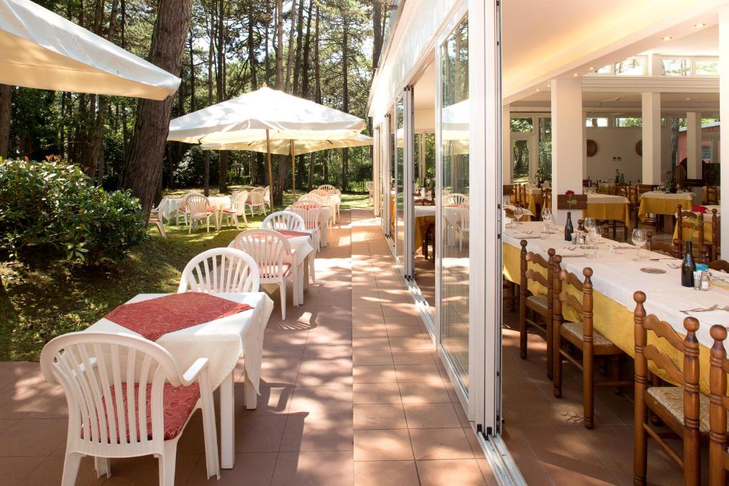 利尼亚诺萨比亚多罗Hotel San Marco的一间设有白色桌椅和树木的餐厅