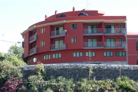 圣克鲁斯-德拉帕尔马加雷翁公寓酒店的一座红色的建筑,旁边设有阳台