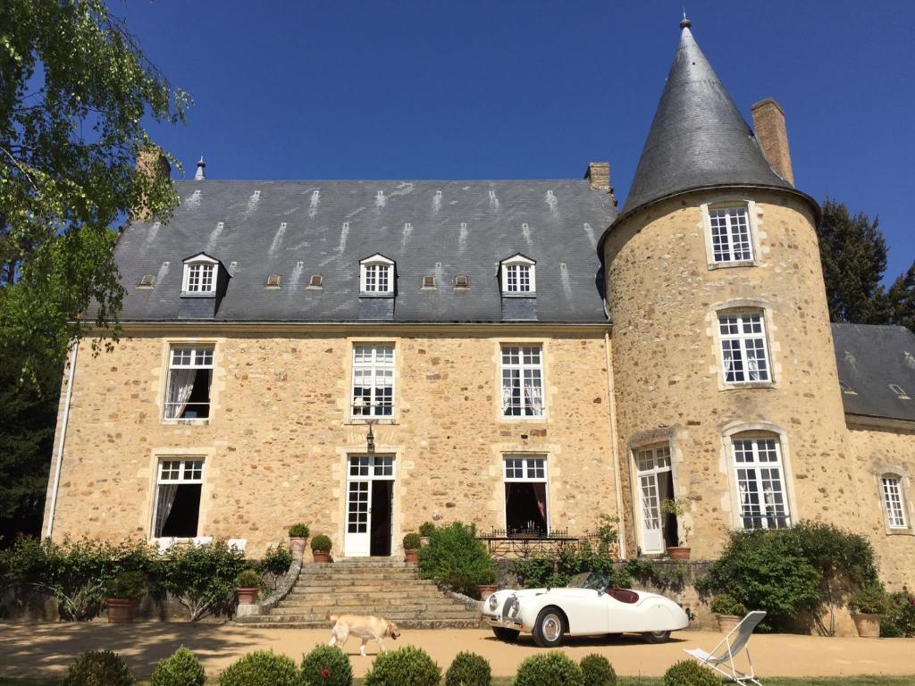 伊芙尔莱韦克Chateau de Vaux的一座大型石头建筑,前面有一辆白色的汽车