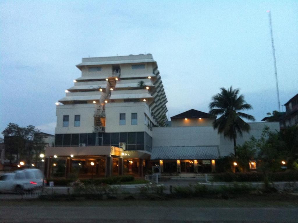 春蓬帕拉多恩旅馆的一座白色的大建筑,前面有一棵棕榈树