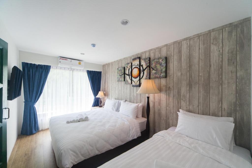 坤敬Anchan Laguna Hotel โรงแรมอัญชันลากูน่า的酒店客房设有两张床和窗户。