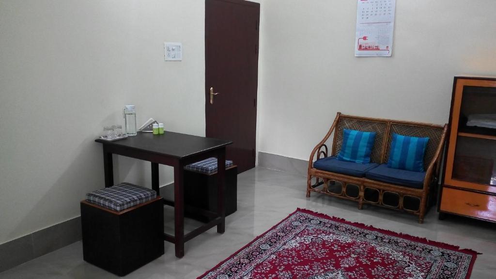 古瓦哈提Cozy Living的客房配有桌子、椅子和蓝色枕头。