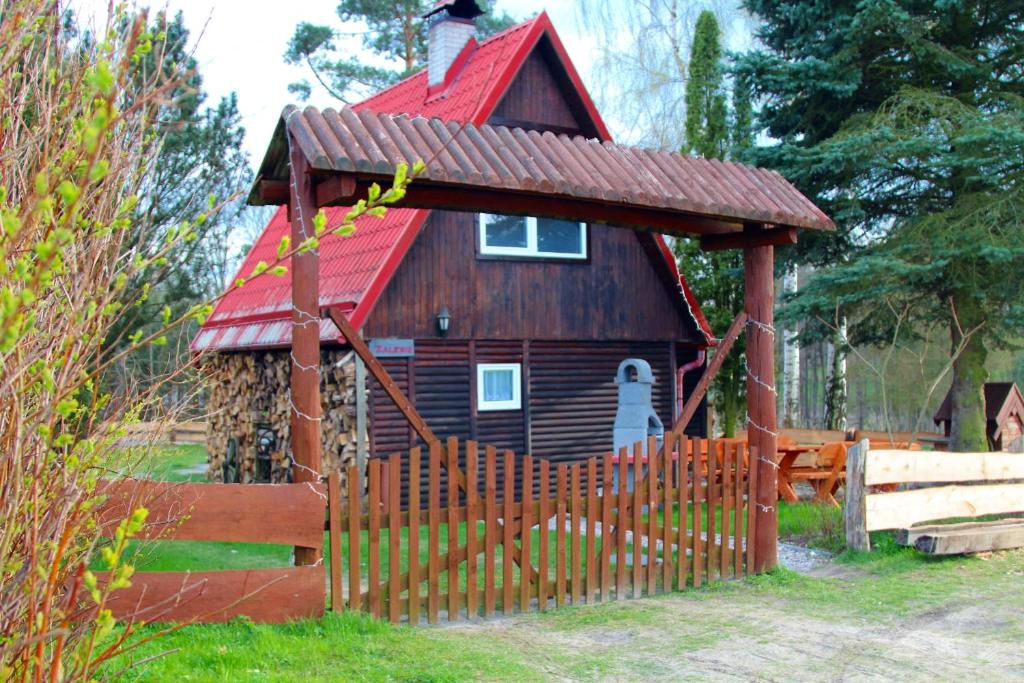 巴尔切沃Domek Zalesie的一座带红色屋顶的木房子,位于栅栏后面