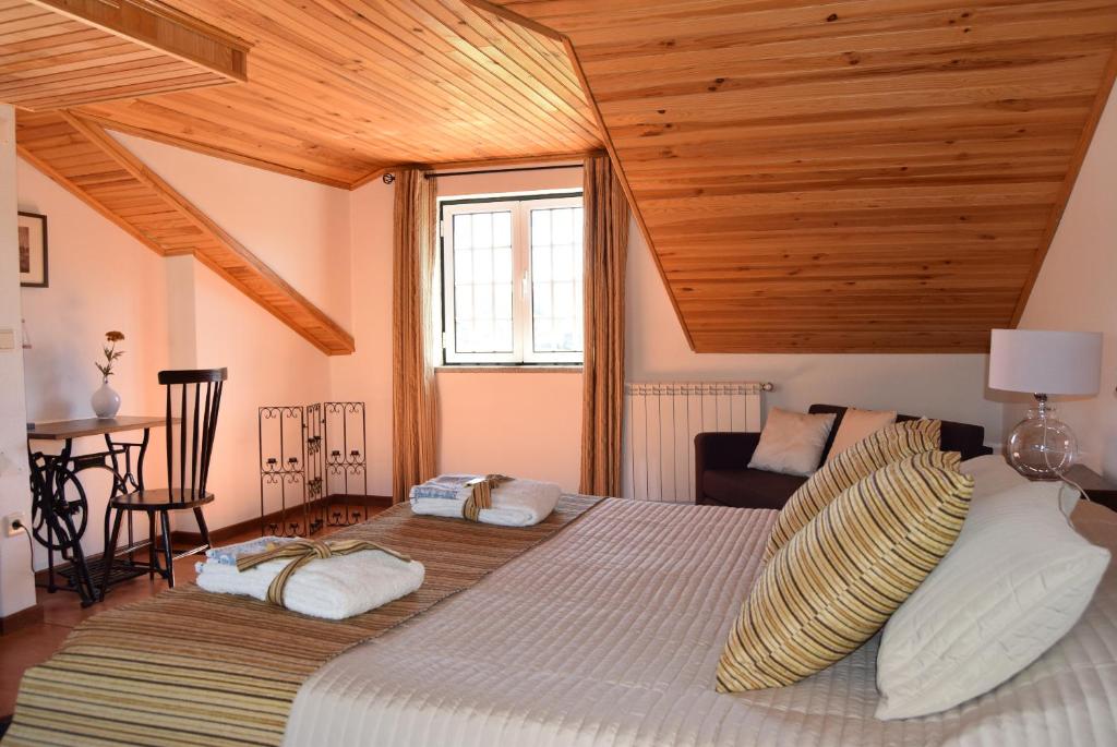 戈韦阿Casa do Chão do Ribeiro的一间卧室设有一张带木制天花板的大床