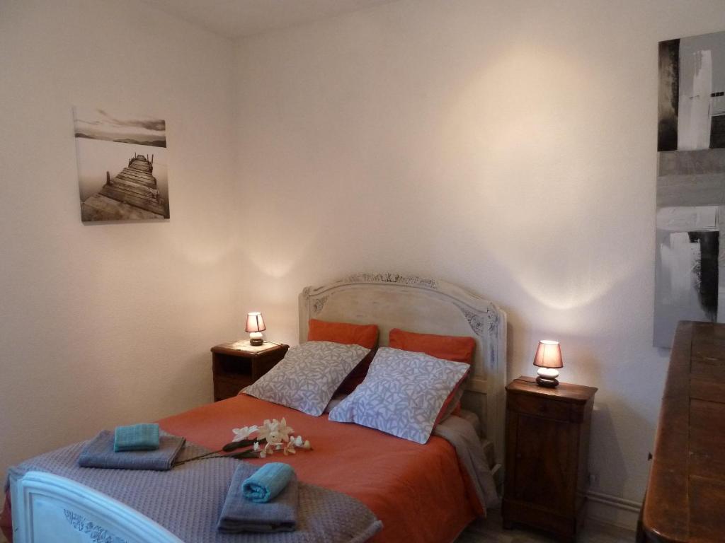 萨尔拉拉卡内达Appartement centre médiéval - Le Cosy de Sarlat的一间卧室配有一张带橙色床单和两盏灯的床。