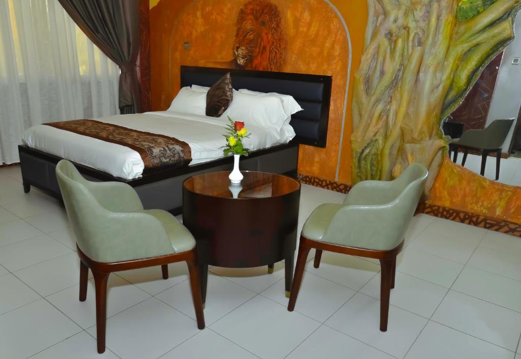 内罗毕拉戈斯酒店的一间卧室配有一张床、两把椅子和一张桌子