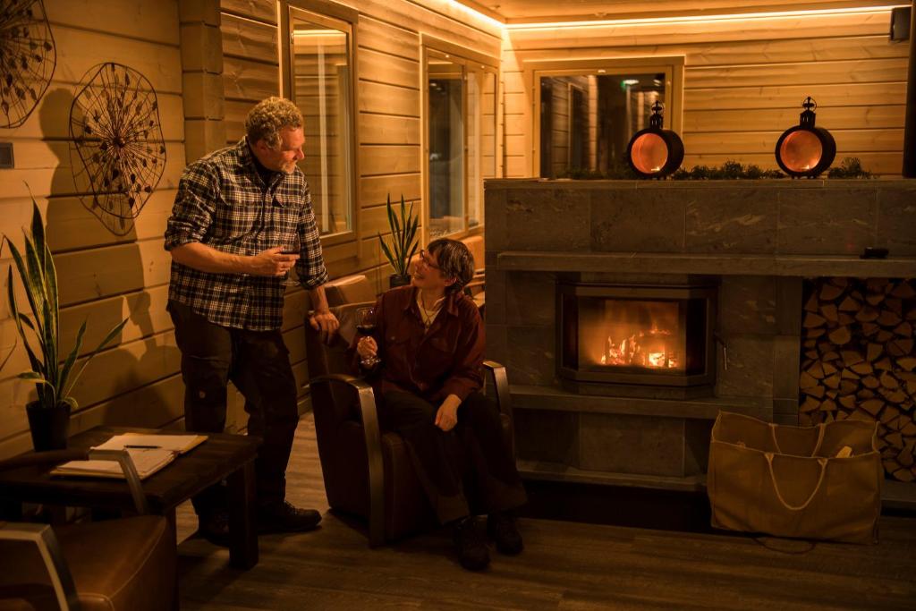 佩洛Valkea Arctic Lodge的男人和女人站在带壁炉的客厅里