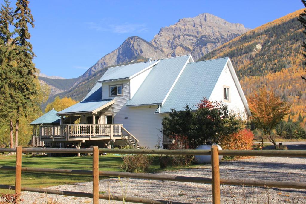戈尔登Bear Paw Lodge的白色的房子,设有门廊和山地背景