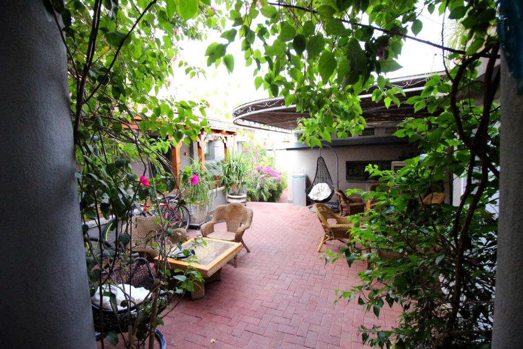 埃拉特日落宾馆的户外庭院配有桌椅和植物。