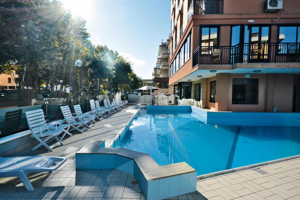 切塞纳蒂科Hotel Apollo的一座带躺椅的游泳池和一座建筑