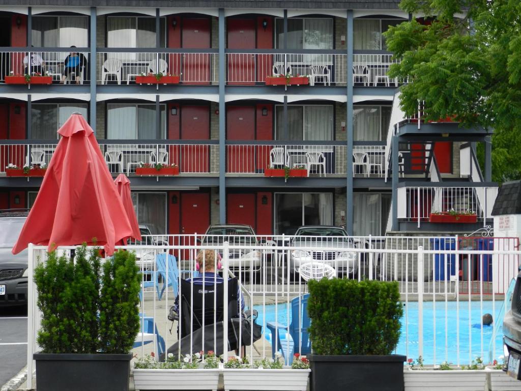 尼亚加拉瀑布瀑布国王酒店的一座带游泳池和红伞的建筑