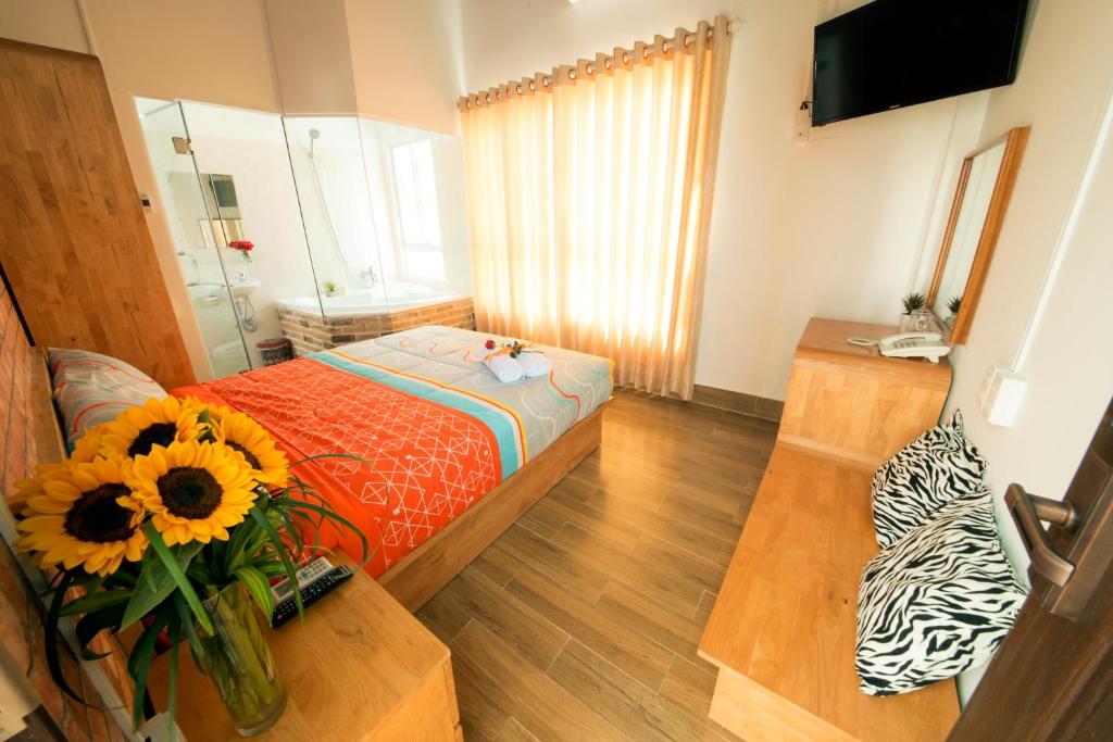 芽庄安娜之家旅舍的一间设有一张床和一张桌子的房间,上面有向日葵花瓶