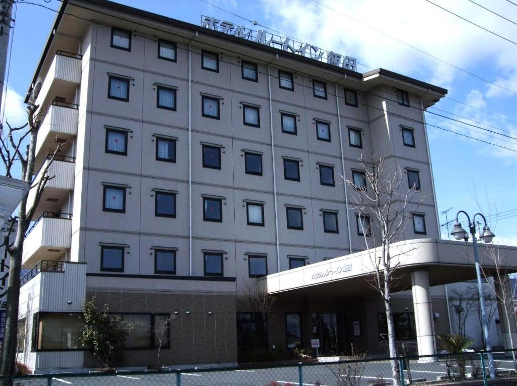 饭田市埃达路特酒店的一座白色的大建筑,有很多窗户