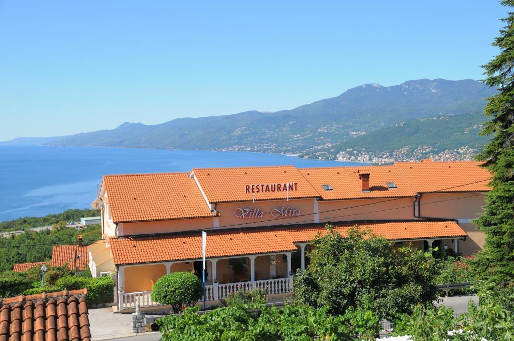 卡斯塔夫Villa Mira的一座拥有橙色瓷砖屋顶的建筑,毗邻水面
