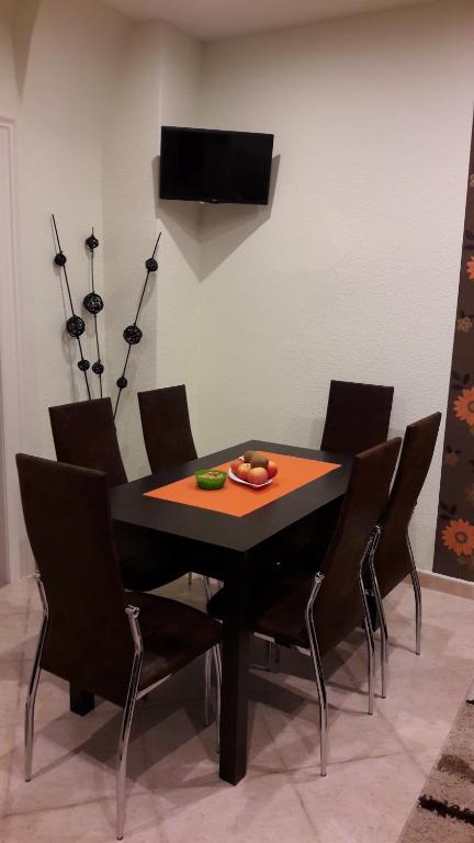 埃格尔Relax apartman的一张带椅子的黑色餐桌和电视