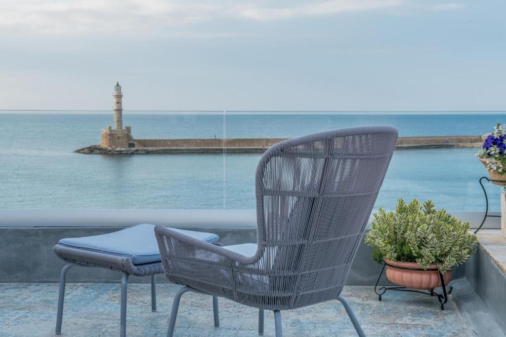 干尼亚Residenza Vranas Boutique Hotel的一张椅子坐在一个俯瞰大海的阳台上