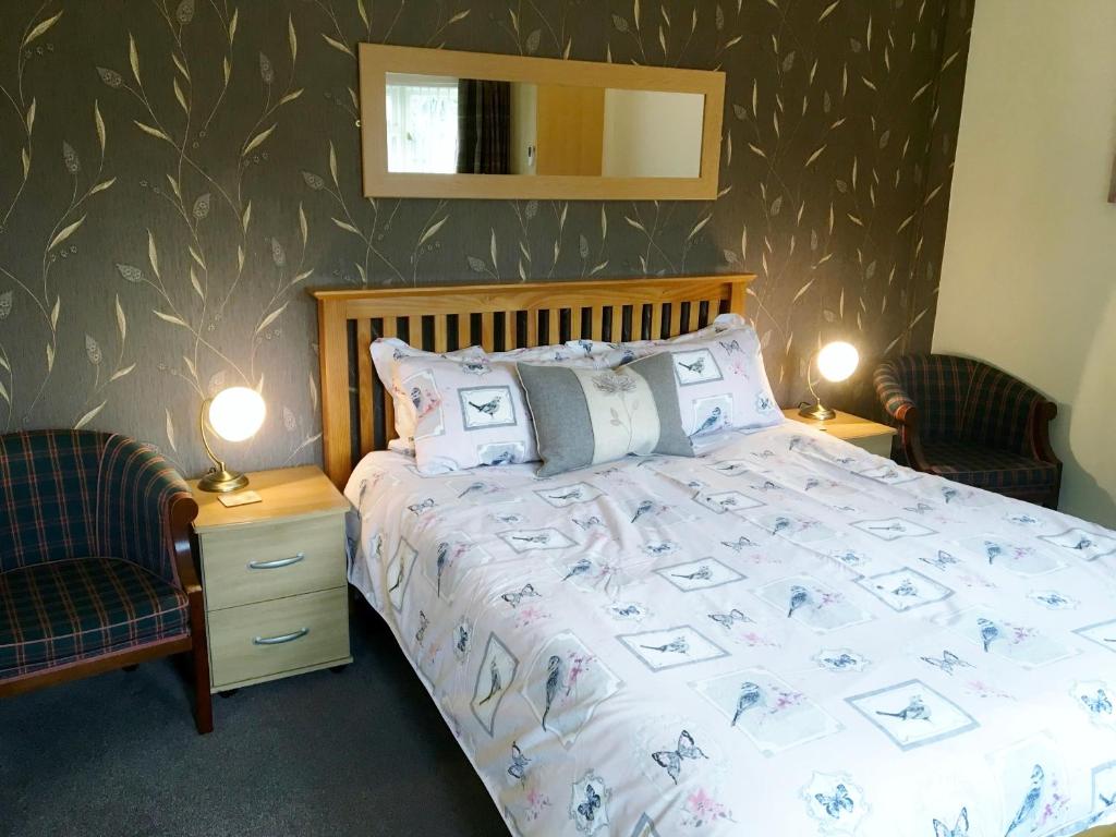 亨斯坦顿阿什莉旅舍的一间卧室配有一张床、两把椅子和镜子